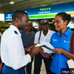 Home 19 세인트루시아 비자 정보 - A detailed airport arrival scene at Saint Lucia’s Hewanorra International Airport, showing a diverse...